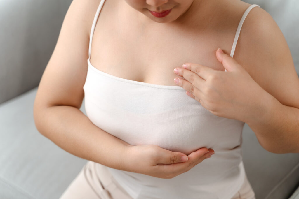 asian woman checking lumps on her breast for signs of breast can
